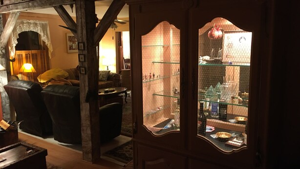 Un salon chaleureux avec une cheminée, un plafond en bois et une vitrine.