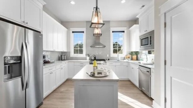 A modern kitchen with white cabinetry, stainless steel appliances, and a central island. - Charming 3 bedroom beach house in Cape Charles, VA  (Cape charles)