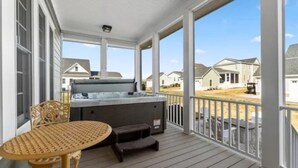 A covered porch with a hot tub, a table, and a chair. - Charming 3 bedroom beach house in Cape Charles, VA  (Cape charles)