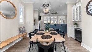 A spacious dining area with a long wooden table, black chairs, and a modern chandelier. - Charming 3 bedroom beach house in Cape Charles, VA  (Cape charles)