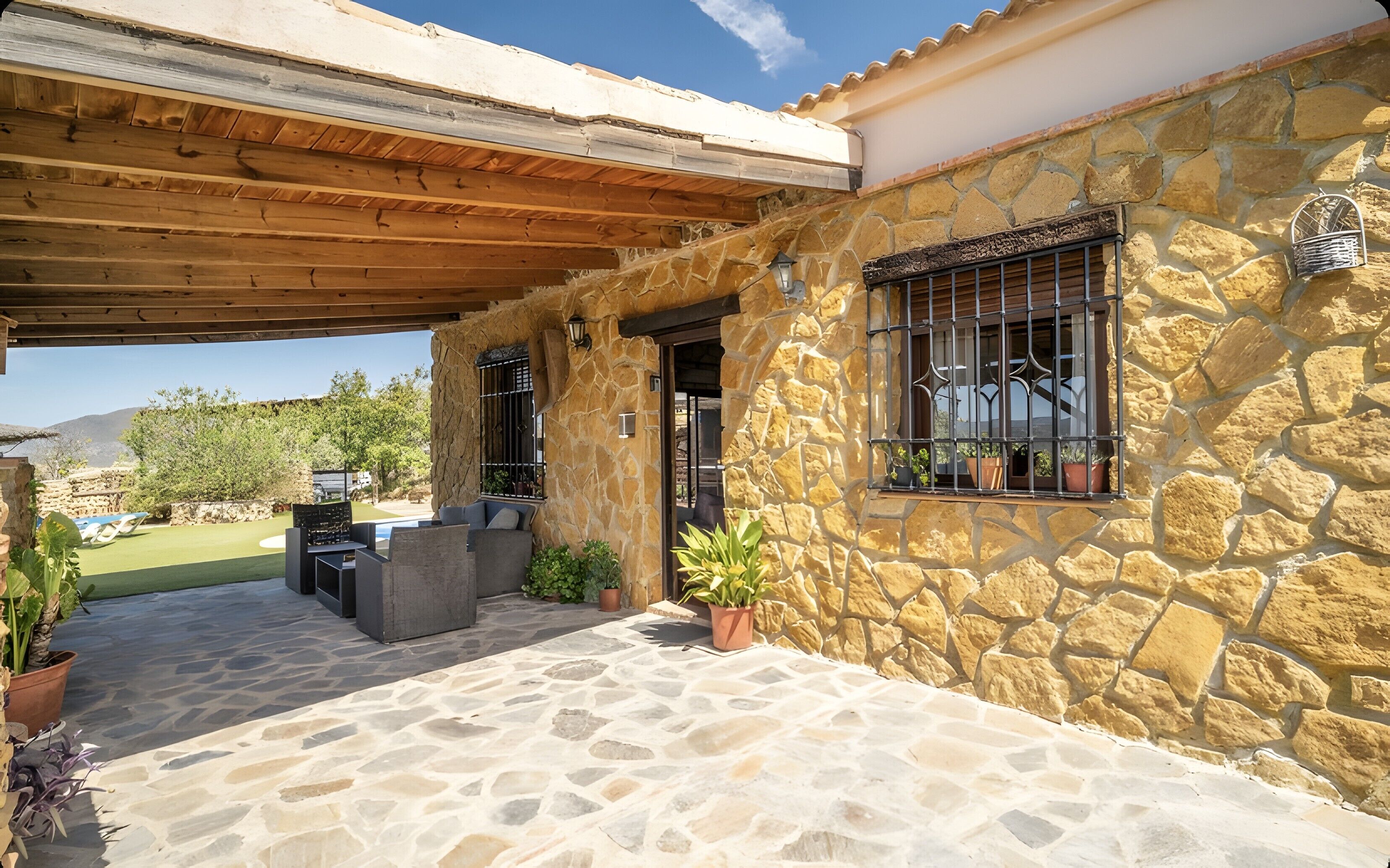 Une maison en pierre dotée d’un patio couvert, d’un espace salon extérieur et offrant une vue sur le paysage.