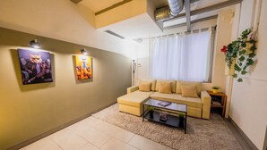 A living room with a beige sofa, a coffee table, and two wall-mounted paintings.