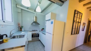 A compact kitchen with white cabinets, a stove, oven, and a refrigerator. There is a window with a view, a sink, and a coffee maker on the counter.