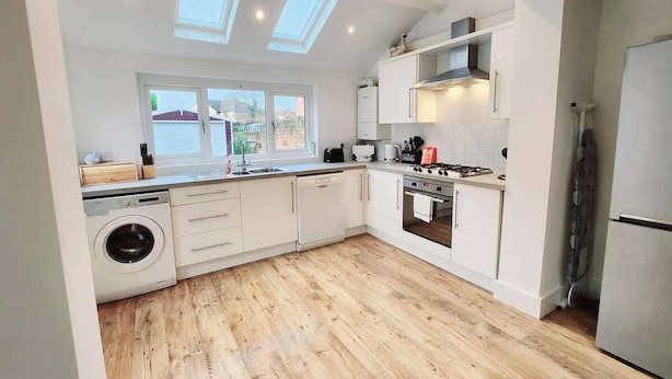 A modern kitchen with a washing machine, a stove, and a refrigerator. - Beautiful 4BR Home near Chester Racecourse (Chester)