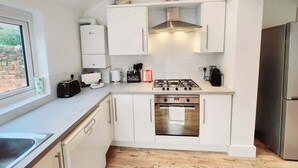 A modern kitchen with white cabinetry, a gas stove, a built-in oven, and a stainless steel refrigerator. - Beautiful 4BR Home near Chester Racecourse (Chester)