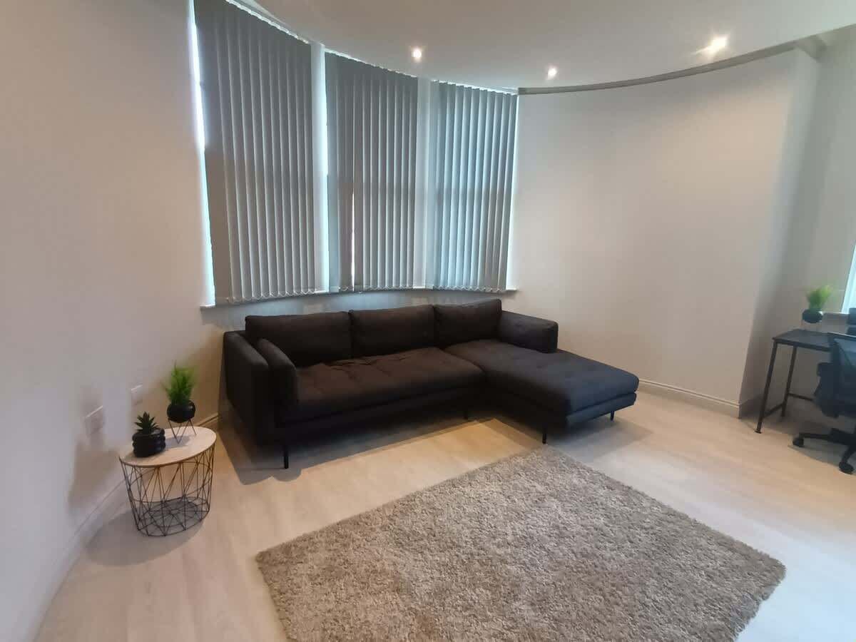 A modern living room with a sectional sofa, a round coffee table, and a large area rug.