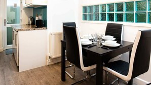 Un comedor con una mesa negra, sillas blancas y un reloj en la pared.