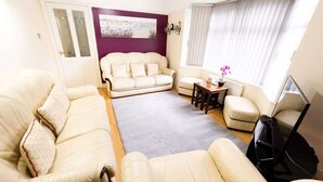 Una sala de estar con sofá, sillones, una mesa de centro y televisor.