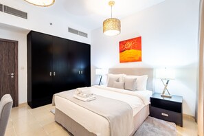 A bedroom with a bed, a wardrobe, a nightstand, and a painting on the wall. - Enjoy JBR Sea & Dubai Eye & Marina View (Dubai)
