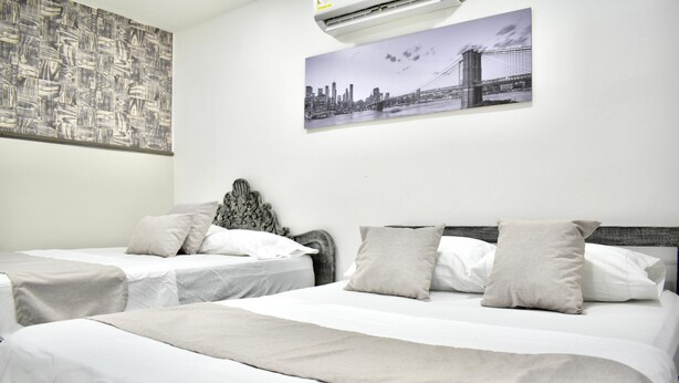 A hotel room with two beds, a cityscape painting, and an air conditioning unit. - HOTEL SANTO RIO SUITE (Santa Marta)