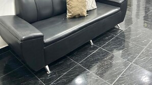 A black leather sofa with a beige pillow and a mirrored wall above it. - HOTEL SANTO RIO SUITE (Santa Marta)