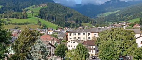 A town nestled in a valley with buildings, trees, and mountains in the background.