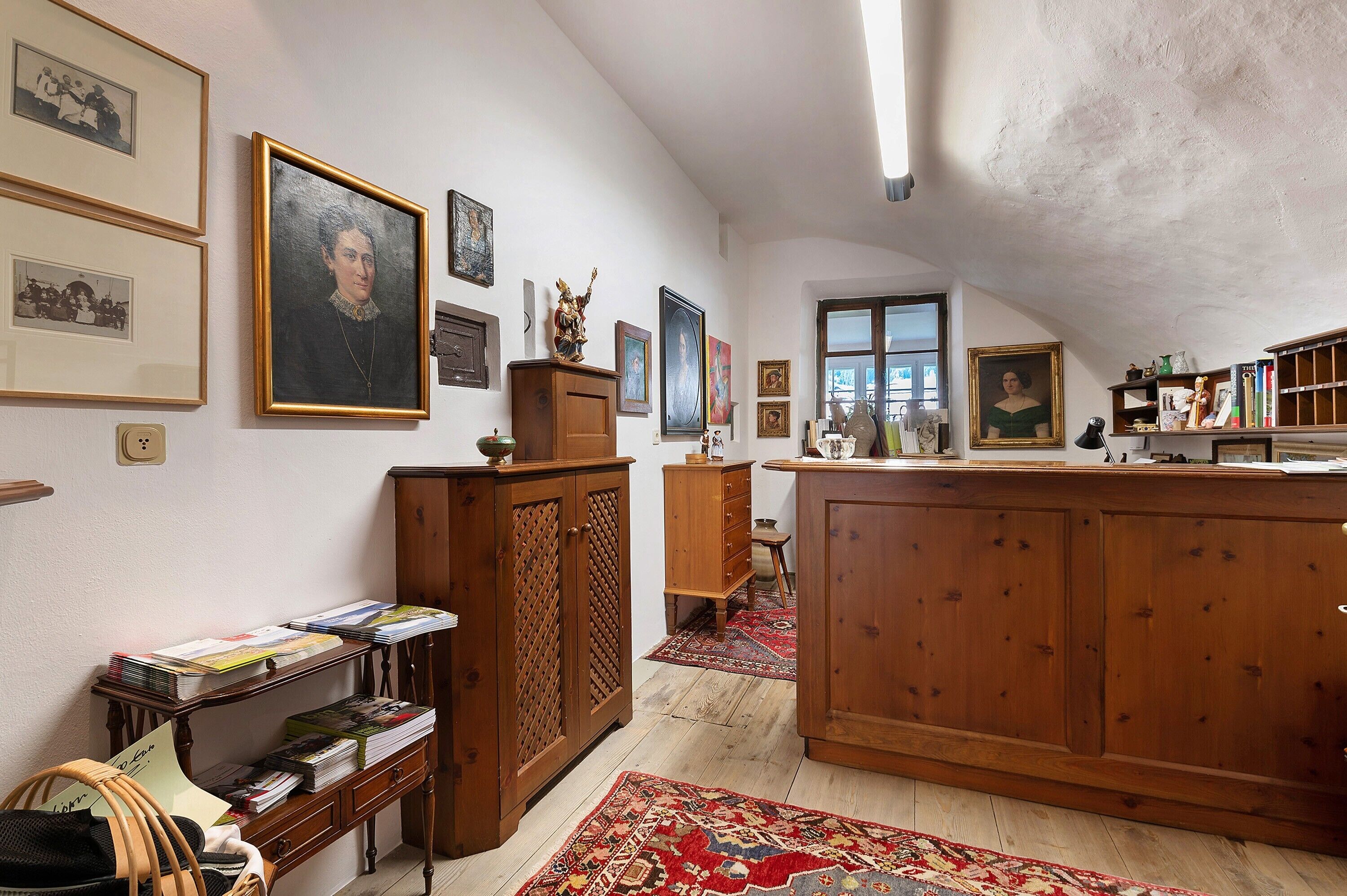 Une pièce avec des meubles de rangement en bois, une bibliothèque et des tableaux encadrés accrochés aux murs.