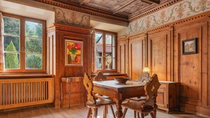 A dining room with a wooden table and chairs, a radiator, and a window with a view of trees. - Room 'Hirschen Fürstenzimmer' with Mountain View, Shared Terrace and Wi-Fi (Sarentino)