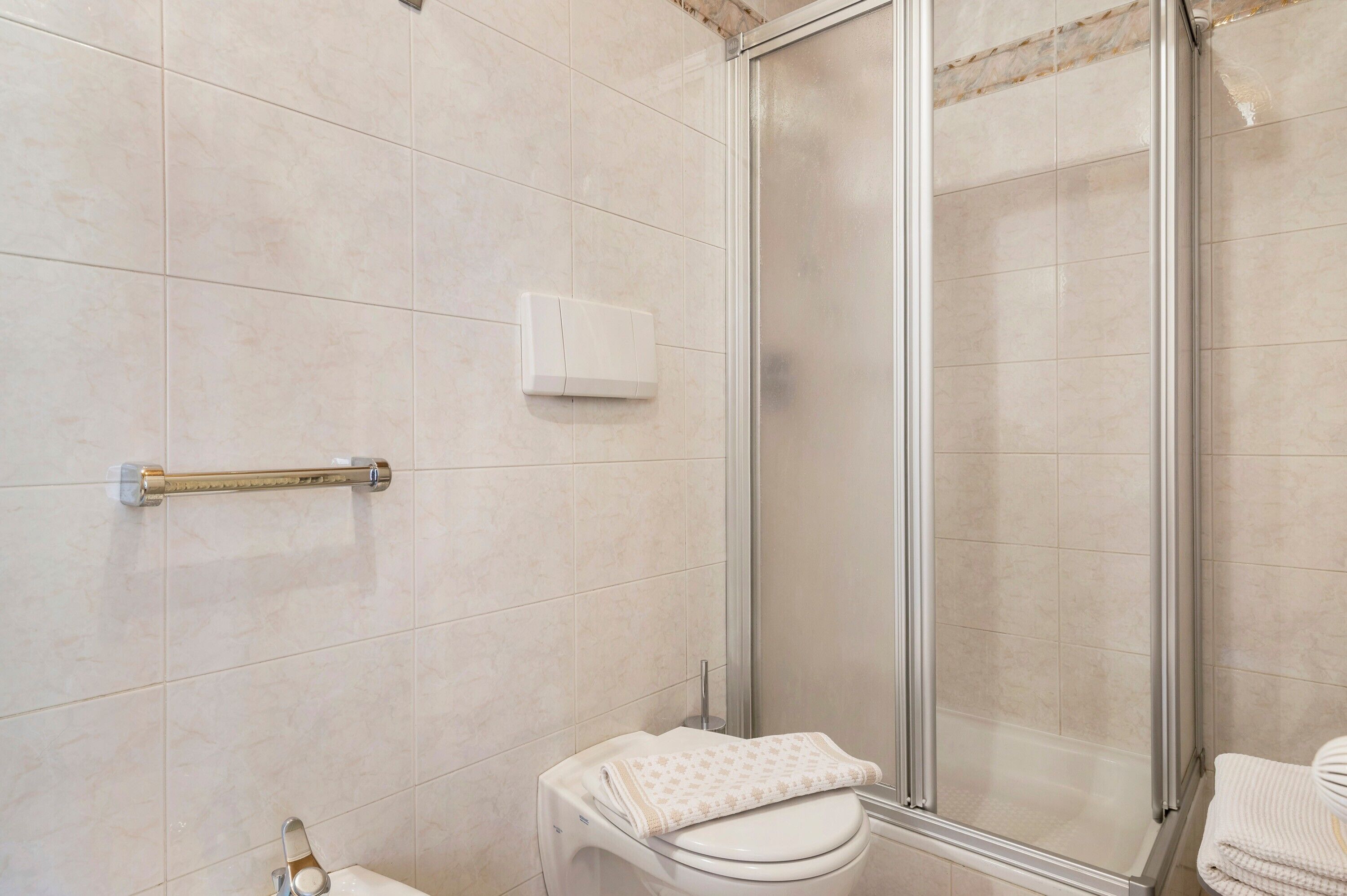 A bathroom with a toilet, a hand dryer, and a glass shower enclosure.