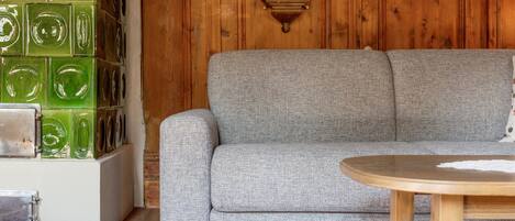 Una habitación con un sofá gris, una mesa de madera y una pared con azulejos de vidrio verde.