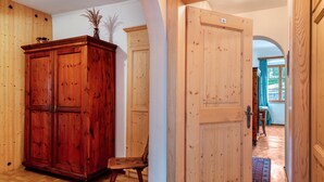 A wooden hallway with a large cabinet, a chair, and a door leading to another room.