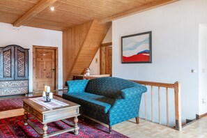 Une pièce avec un plafond en bois, un canapé bleu à motifs, une armoire en bois et un tableau accroché au mur.