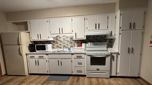 A kitchen with white cabinets, a microwave, a stove, and a refrigerator.