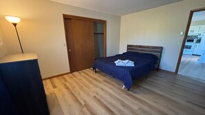 A bedroom with a bed, a desk, and a wardrobe.