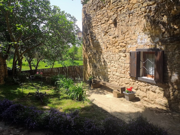 A rustic stone building with a wooden bench and potted plants.