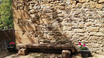 Un mur de pierre avec un banc en bois et des plantes en pot.