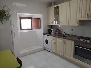 A kitchen with a washing machine, microwave, sink, and stove.
