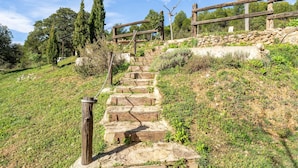 A stone staircase leading uphill with a wooden fence and trees in the background. - Country House 'La Sala' with Mountain View, Shared Pool and Wi-Fi (Peñarroya De Tastavins)