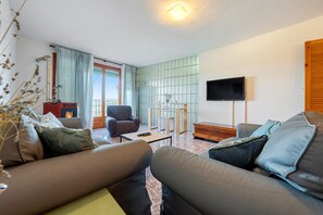 A living room with a sofa, armchair, coffee table, and a flat-screen TV mounted on the wall.