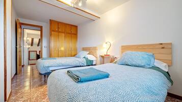 Een hotelkamer met twee bedden, een houten kledingkast, een nachtkastje met een lamp, en een badkamer op de achtergrond.