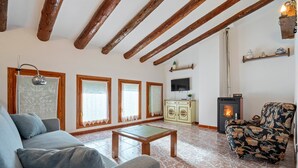 Una sala de estar con sofá, sillón, mesa de centro de madera, chimenea, televisor y un aparador decorativo.