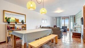 Una sala de estar con una mesa de comedor, un banco y lámparas colgantes.