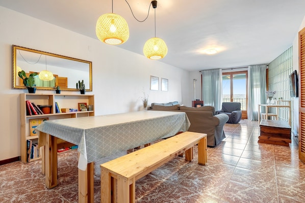 A living room with a dining table, bench, and hanging lights.