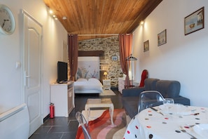 Une pièce comprenant un lit, un canapé, une table à manger avec des couverts, un extincteur et une horloge au mur.