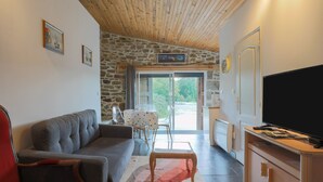 Una sala de estar con un sofá, una mesa de centro de madera, un televisor y una pared de piedra.