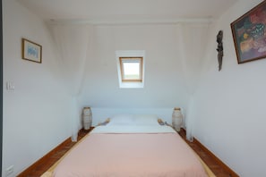 Un dormitorio con una cama individual, un tragaluz, un ventanal pequeño y un adorno de pared decorativo.