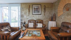 A living room with leather sofas, a coffee table with magazines, a framed picture, and decorative items on the walls. - Maison "Keryanti" with Jacuzzi, Private Terrace, Garden & Wi-Fi (Plouégat-Moysan)