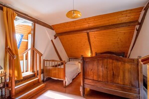 Un dormitorio tipo loft con vigas de madera, una escalera de madera, dos camas y una lámpara colgante.