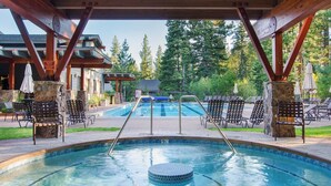 A pool area with a hot tub, lounge chairs, and a covered patio.