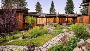 A wooden cabin with a stone pathway and lush garden.