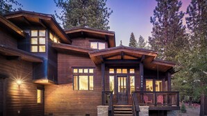 A large, modern log cabin with multiple windows and a prominent front porch.