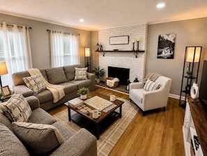 A living room with a fireplace, two sofas, a coffee table, and a bookshelf.