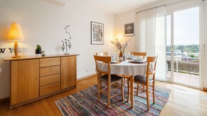 A dining area with a table set for four, a wooden cabinet, and a view through a glass door.