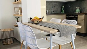 Eine moderne Küche mit weißen Schränken, einem Holzespeisetisch und weißen Stühlen.