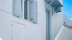 Ein weißes Gebäude mit Treppe, Tür und Fenster.