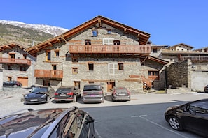 Un bâtiment en pierre doté de balcons et où sont garées des voitures.
