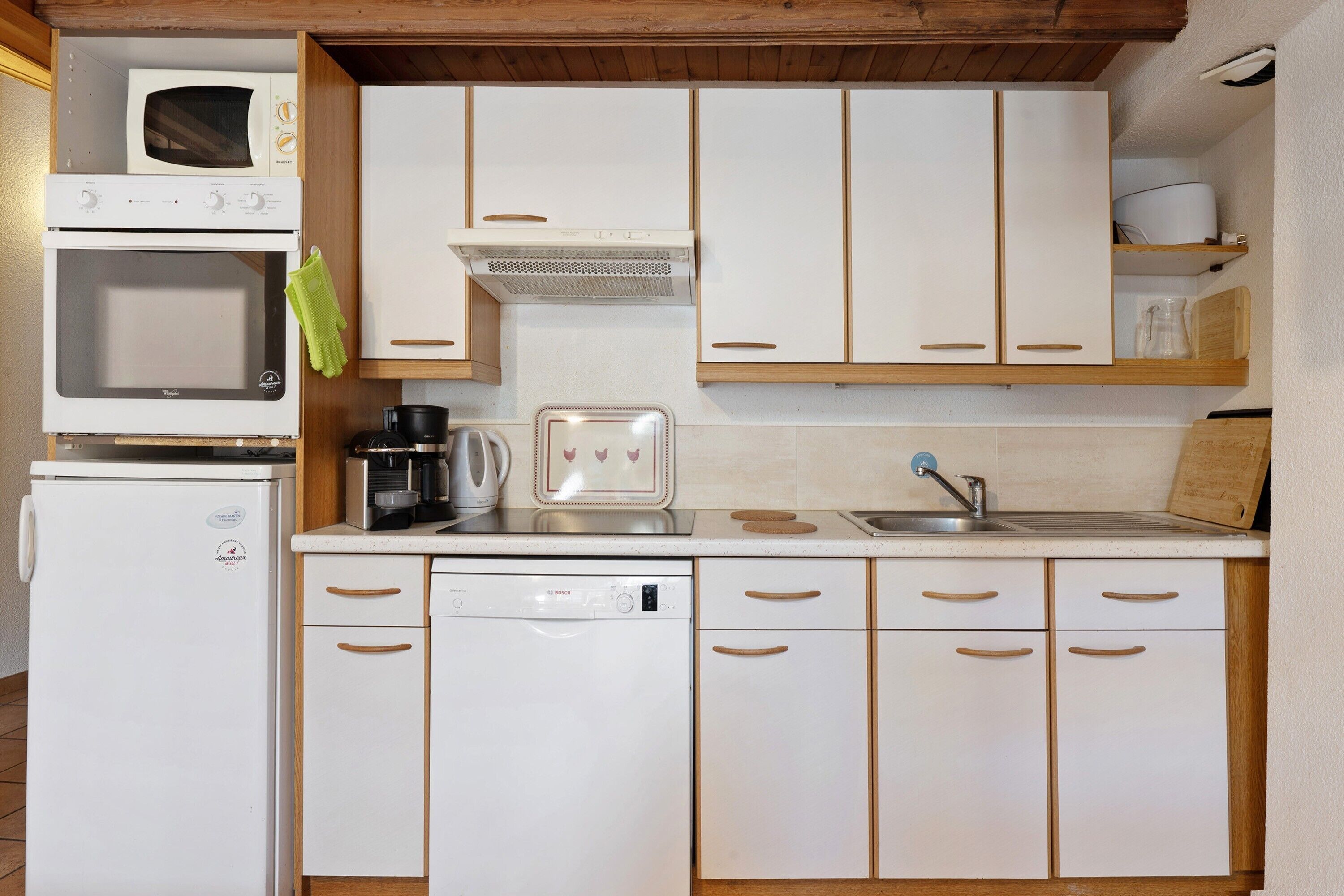 A compact kitchen with a microwave, oven, coffee maker, toaster, and dishwasher.