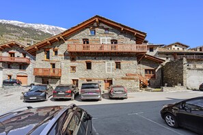 Un edificio de piedra con balcones y coches aparcados.