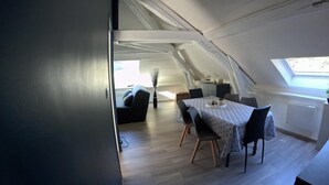 Un dormitorio estilo loft moderno con techo inclinado, tragaluces y comedor con mesa y sillas.