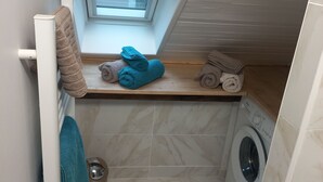 Un baño pequeño con tragaluz, lavadora y toallas ordenadas.